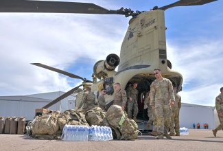 Members of the United Stated military unload relief supplies from one of three helicopters, which arrived in the island on Friday (October 31), at the Caribbean Military Academy School of Aviation in Kingston.