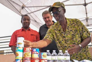 Minister of Local Government and Community Development, Hon. Desmond McKenzie (right), examines food supplies donated by nonprofit organisation, Global Empowerment Mission (GEM). The supplies, handed over on Friday (October 31), will support 50 residents at the Desmond McKenzie Transitional Centre for the Homeless in downtown Kingston. Looking on are Mayor of Kingston, Councillor Andrew Swaby (left), and Founder/President of GEM, Michael Caponi
