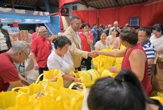 Prime Minister, Dr. the Most Hon. Andrew Holness (fourth left) greets a volunteer, during a visit to the Chinese Benevolent Association’s (CBA) headquarters on Old Hope Road on Thursday (Nov. 13), to observe relief items being packaged for distribution to families affected by Hurricane Melissa. He is joined by President of the CBA, Vincent Chang (second left).