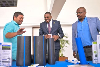 Minister without Portfolio in the Ministry of Economic Growth and Infrastructure Development with responsibility for Works, Hon. Robert Morgan (centre), and President, Incorporated Masterbuilders Association of Jamaica (IMAJ), Richard Mullings (right), in discussion with Divisional Manager for Waterworks, Isratech, Gregory Chin Loy, about the high-density polyethylene pipes manufactured in Jamaica, during the Incorporated Masterbuilders Association of Jamaica (IMAJ) seminar, held at the Jamaica Conference Centre in downtown Kingston, on November 25.

