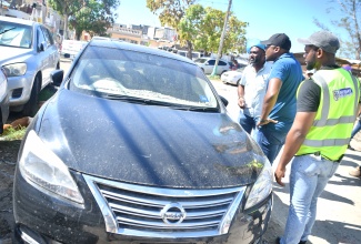 Minister without Portfolio in the Ministry of Economic Growth and Infrastructure Development, Hon. Robert Morgan (second left); Minister without Portfolio in the Office of the Prime Minister responsible for Science, Technology and Special Projects, Dr. the Hon. Andrew Wheatley (left); and Mayor of Montego Bay, Councillor Richard Vernon, look at mud on several cars in Catherine Hall, St. James, during a tour on Friday (Nov. 14) to get a firsthand look at the extent of damage from floodwaters associated with Hurricane Melissa.