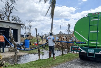 Members of the Doctors without Borders team truck water to homes in Slipe, St. Elizabeth.

