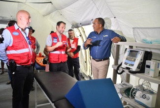 Minister of Health and Wellness, Dr. the Hon. Christopher Tufton (left) converses with PAHO/WHO Country Representative, Ian Stein during the deployment ceremony for the Spanish emergency field hospital in Falmouth , Trelawny on Friday (November 7). 