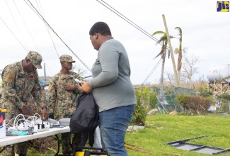 A resident waits to have his device charged at the charging station manned by members of the Jamaica Defence Force (JDF). Occasion was a post-hurricane Melissa support project staged by For Your Image Consultancy (FYI) and Friends, at the William Knibb Memorial High School in Falmouth, Trelawny, on Wednesday (November 5).