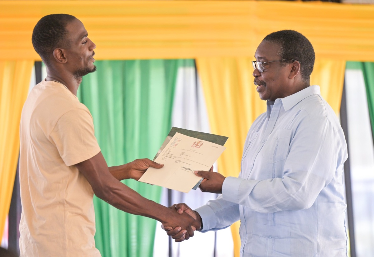 Minister without Portfolio in the Ministry of Economic Growth and Infrastructure Development with responsibility for Land Titling and Settlements, Hon. Robert Montague (right), hands a St. Elizabeth resident his land title, during a ceremony held at the Lacovia Community Centre in the parish on Friday (December 12).

