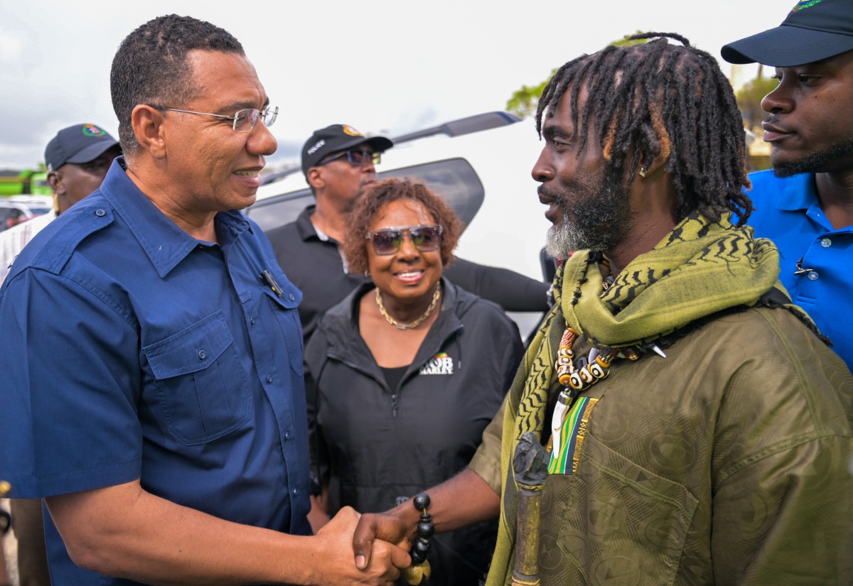 Prime Minister, Dr. the Hon. Andrew Holness (left), shaking hands with Chief of the Accompong Maroons in St. Elizabeth, Richard Currie, during a visit to the community on Sunday (November 30). Looking on at centre is Minister of culture, Gender, Entertainment and Sport, Hon. Olivia Grange.

