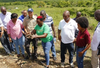 Executive Director of the Jamaica 4-H Clubs, Peter Thomas (third right), observes while Brand Ambassador for the Wambugu Apple, developed in Kenya, Catherine Wambugu (fourth right), leads a recent planting exercise held at the Ebony Park Agro Park in Clarendon.

