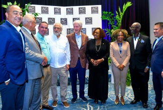 Minister of Culture, Gender, Entertainment and Sport, Hon. Olivia Grange (fourth, right), and other Cabinet Ministers, share a moment with Former President of the United States Bill Clinton (centre) during a reception held in his honour at the AC Hotel in Kingston on Thursday evening (December 4). From left are Minister of Health and Wellness, Dr. the Hon. Christopher Tufton; Minister of Justice and Constitutional Affairs, Hon. Delroy Chuck; Minister of Energy, Transport and Telecommunications, Hon. Daryl Vaz; Businessman Rolando Gonzalez-Bunster; Minister of Education, Skills, Youth and Information, Senator Dr. the Hon. Dana Morris Dixon; Minister of Local Government and Community Development, Hon. Desmond McKenzie; and Minister of Water, Environment and Climate Change, Hon. Matthew Samuda.

