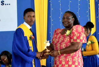 Acting Principal of Jonathan Grant High School, Cheryl Shippey (right), presents a trophy to Top Student, Sanjay Tennant, at the recent graduation ceremony held at the institution in Spanish Town, St. Catherine.

