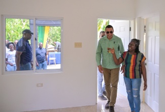 Prime Minister, Dr. the Most Hon. Andrew Holness (left), accompanies Cynthia Johnson on a tour of her new house in Rock River, Clarendon, on Friday (December 19). The two-bedroom house was presented under the New Social Housing Programme (NSHP).


