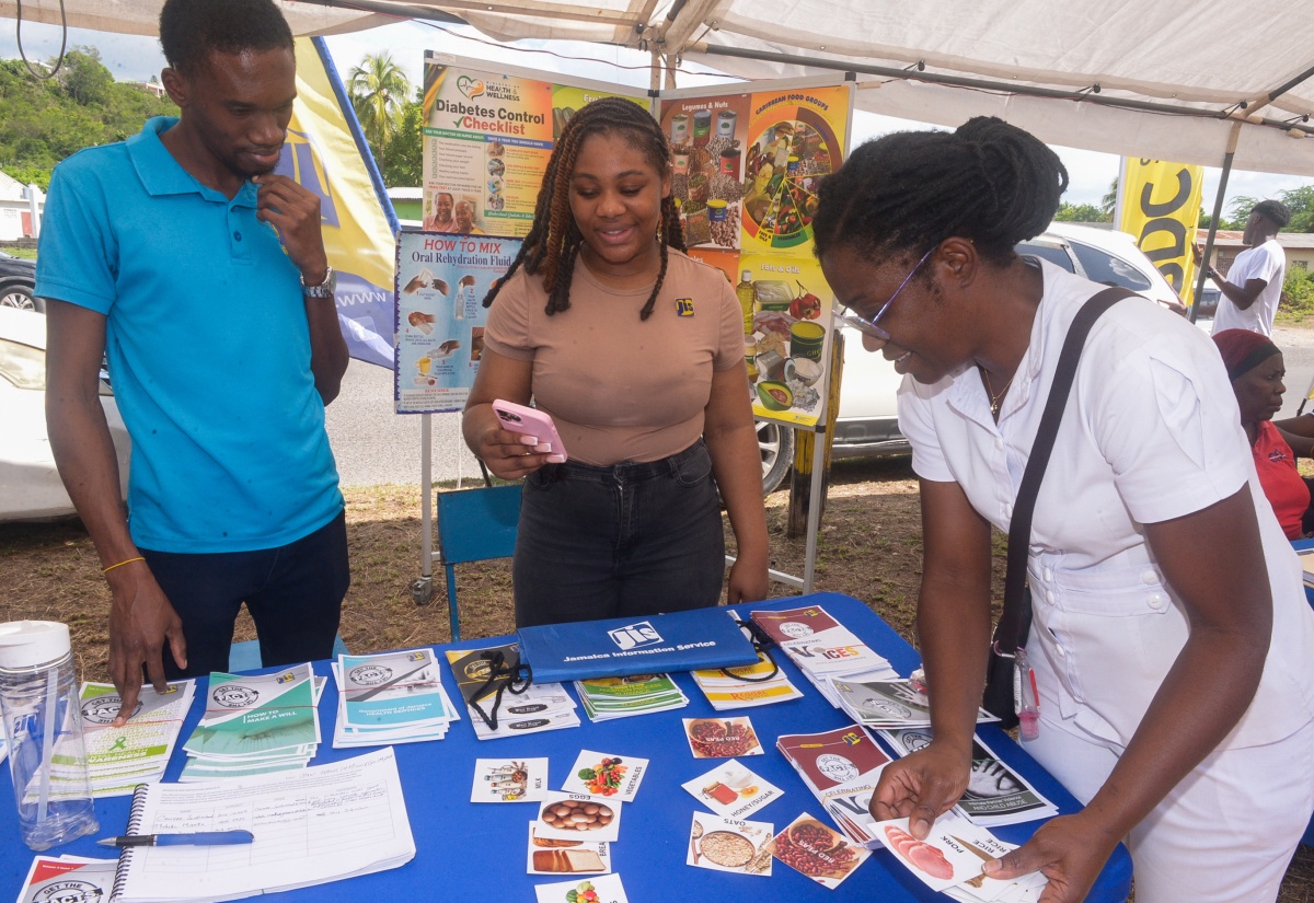 Clerical Officer in the Public Relations and Marketing Department of the Jamaica Information Service (JIS), Rushawn Wallace (left) and Special Projects Officer, JIS, Romona Geohaghan (centre), look on as a nurse plays a game of "balanced diet", where she  uses ingredients represented on cue cards to create a healthy meal. The occasion was the recent staging of the Lauriston/Thompson Pen Community 4-H Club