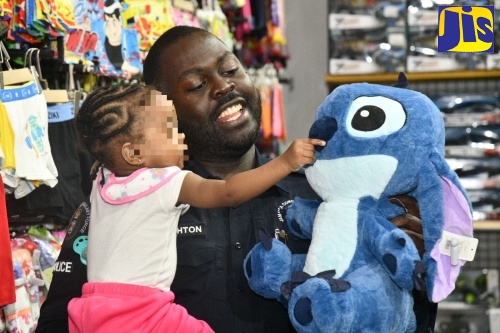 Superintendent of Police Throyville Haughton, attached to the St. Catherine South Police Division, shares a warm moment with an infant as he presents her with a stuffed toy during the ‘Shop with a Cop’ initiative, held on December 19 at Portmore Pines Plaza in St. Catherine.