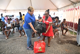 State Minister in the Ministry of Health and Wellness, Hon. Krystal Lee (left), hands over a care package to expectant mother Shanae Cooper-Robinson, during a maternal health outreach at the Black River Health Centre in St. Elizabeth in November.

