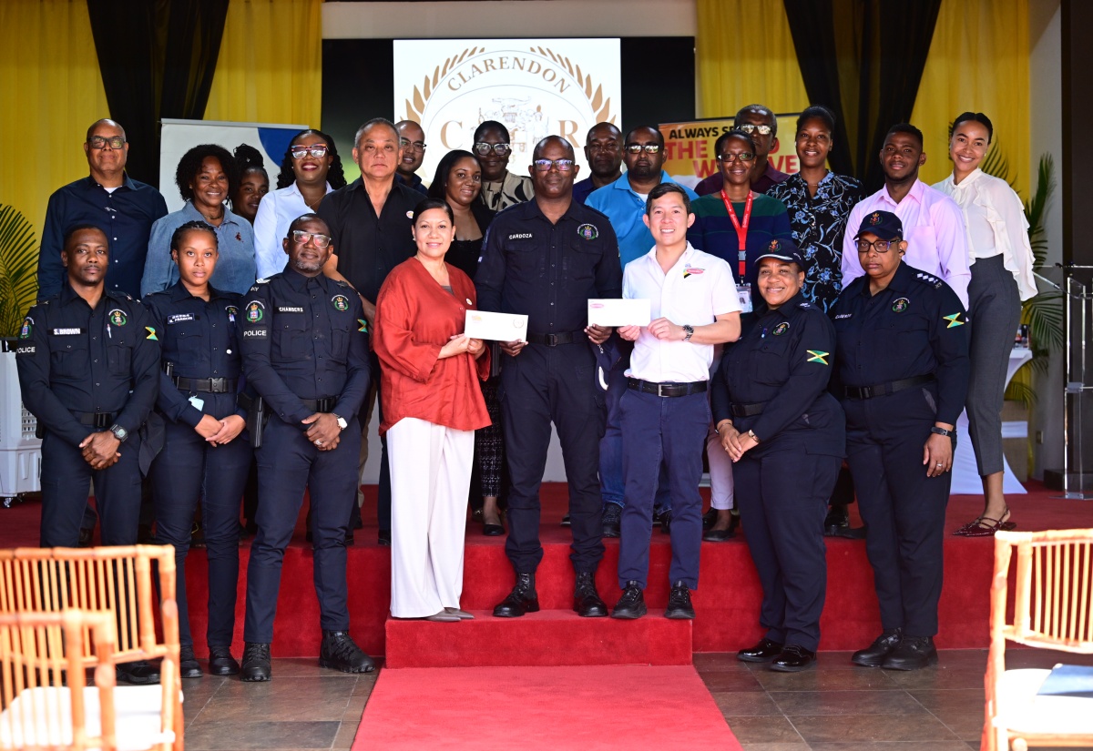 Custos of Clarendon and Juici Patties Director, Hon. Edith Chin (fourth left), and Director at Continental Baking Company, Craig Hendrickson (third right), hand over cheques totalling $2 million to Head of Operations for the Clarendon Police, Superintendent Anton-Gur Cardoza (fourth right), towards the Jamaica Constabulary Force (JCF) Shop With a Cop initiative. Members of the JCF, Juici Patties staff and other stakeholders share in the occasion.  The presentation took place on Monday (December 15) at the Verandah, located at Juici Empowerment Park in Clarendon.  

