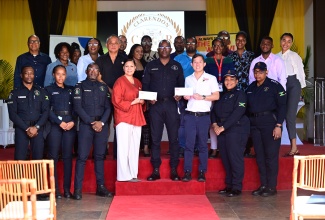 Custos of Clarendon and Juici Patties Director, Hon. Edith Chin (fourth left), and Director at Continental Baking Company, Craig Hendrickson (third right), hand over cheques totalling $2 million to Head of Operations for the Clarendon Police, Superintendent Anton-Gur Cardoza (fourth right), towards the Jamaica Constabulary Force (JCF) Shop With a Cop initiative. Members of the JCF, Juici Patties staff and other stakeholders share in the occasion.  The presentation took place on Monday (December 15) at the Verandah, located at Juici Empowerment Park in Clarendon.  

