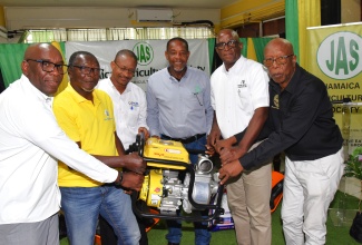 Representative of the Mount Salus Jamaica Agricultural Society (JAS) Branch in St. Andrew, Trevor Jarrett (second left), receives a water pump from agricultural stakeholders including (from left) JAS Chief Executive Officer, Derron Grant; Jamaica Agricultural Commodities Regulatory Authority (JACRA) Acting Director General, Wayne Hunter; JAS President, Owen Dobson; Chief Technical Director of Technical Services in the Ministry of Agriculture, Fisheries and Mining, Orville Palmer, and Jamaica Coffee Growers Association (JCGA) President, Donald Salmon, during Tuesday’s (December 23) handover ceremony at the JAS head office on Church Street, Kingston. Farming inputs, including fertiliser, buckets, water boots, water pumps, and wheelbarrows, were distributed by the JAS to 120 coffee farmers from eastern parishes through collaboration with JCGA, JACRA, and Food for the Poor, as part of post-Hurricane Melissa recovery efforts.

