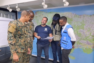 Major Raymond Warren (left) and Captain Omroy Davis (second left), of the Jamaica Defence Force, listen to Regional Deputy Director, United Nations Office for the Coordination of Humanitarian Affairs (OCHA), Rogerio Mobilia (third left), following the December 4 briefing at the National Emergency Operations Centre (NEOC), located at the Office of Disaster Preparedness and Emergency Management (ODPEM), in Kingston.  Also listening (from fourth left) are Data Management Expert, OCHA, Ibrahima Kane and Information Management Officer at OCHA, Randy Warner.

