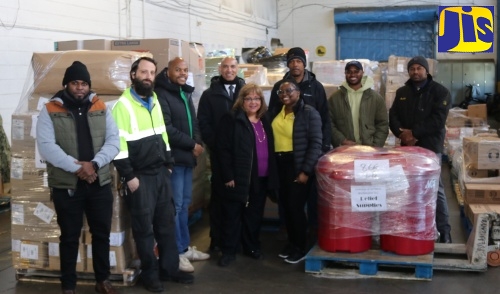 Jamaica’s Ambassador to the United States, His Excellency Major General (ret’d) Antony Anderson (left), President and Chief Executive Officer of EMD Sales International, Elda Devaré (fourth right), and volunteer, Natasha Forrest (second right), proudly display the Jamaican flag before the 40‑foot container of essential supplies bound for the island in support of Hurricane Melissa recovery efforts. Looking on are members of staff from the Embassy of Jamaica and EMD Sales at the company’s Baltimore warehouse in Maryland.