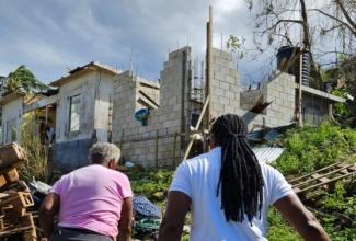 State Minister in the Ministry of Foreign Affairs and Foreign Trade, Honourable Alando Terrelonge (left) accompanies a resident in Eden, St. James, delivering care packages to her home, which was damaged during Hurricane Melissa on October 28.