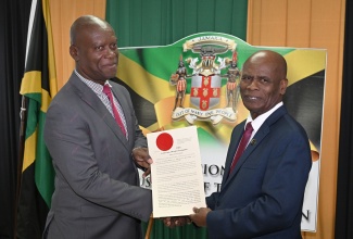 Custos of Kingston, Hon. Steadman Fuller (right) presents new Justice of the Peace (JP) for the parish, Errol Gardner with his instrument of appointment during a commissioning ceremony held on Thursday (Dec. 4), at Kingston Bookshop, downtown Kingston.
