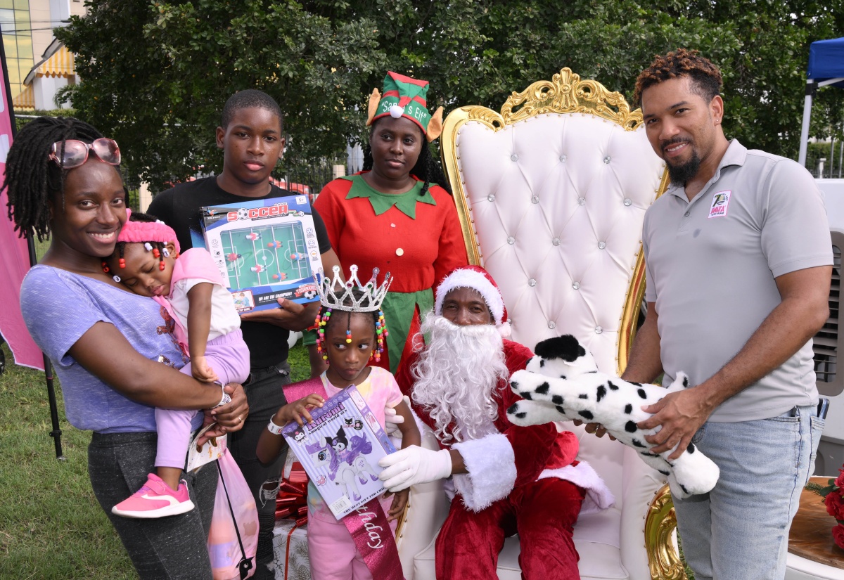 Media Relations Officer at the Jamaica Tourist Board (JTB), Christopher Burke (right), assists Santa and his elf in handing out gifts to attendees at the JTB