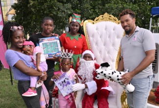 Media Relations Officer at the Jamaica Tourist Board (JTB), Christopher Burke (right), assists Santa and his elf in handing out gifts to attendees at the JTB's recent Christmas Treat held at Devon House in Kingston. The event, held for tourism workers and their families, engaged attendees in festive activities and entertainment, and provided a variety of treats.

