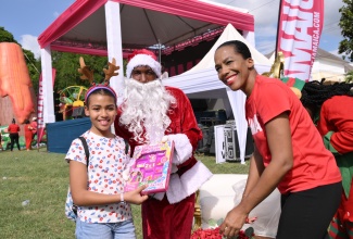 Public Relations and Communications Manager at the Jamaica Tourist Board (JTB), Fiona Fennell (right), assists Santa in presenting a gift to Ameirah Girvan at the JTB’s recent Christmas Treat held at Devon House in Kingston. The event engaged tourism workers and their families in festive activities.
