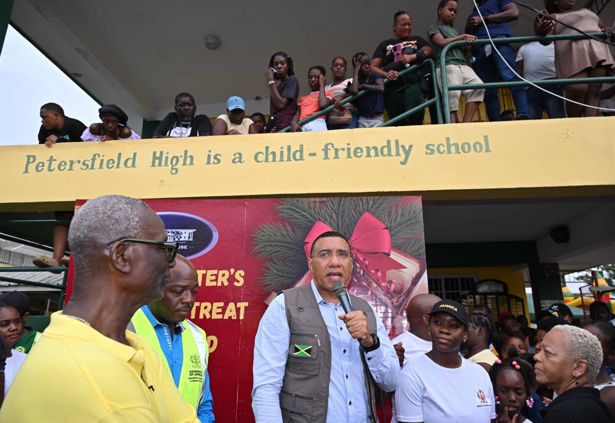 Prime Minister, Dr. the Most Hon. Andrew Holness (centre), addresses residents at the Petersfield High School emergency shelter in Westmoreland during a Christmas treat hosted at the facility on December 13. Listening are Minister of Local Government and Community Development, Hon. Desmond McKenzie (left), and Minister of Labour and Social Security, Hon. Pearnel Charles Jr. (second left).

