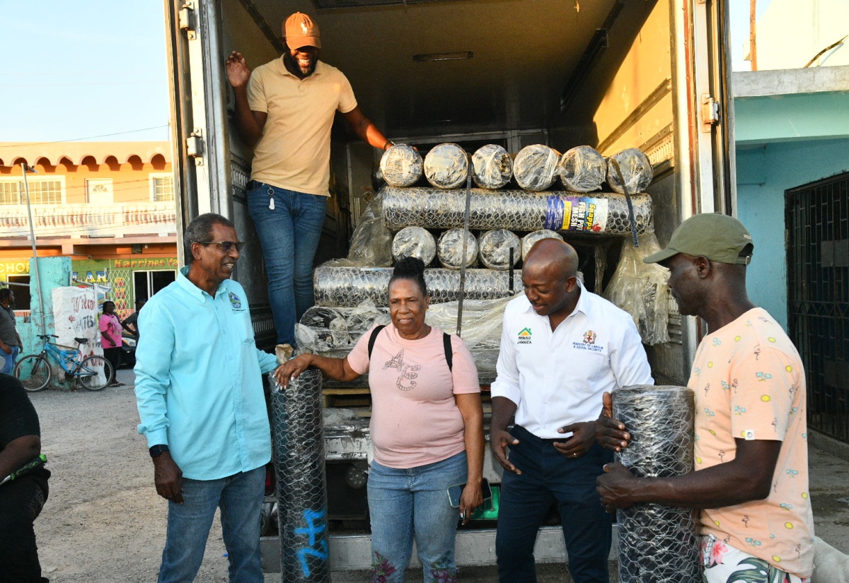 Minister of Labour and Social Security, Hon. Pearnel Charles Jr. (second right), offers words of encouragement to fishers affected by Hurricane Melissa, Annmaureen Spence (second left) and Carlton Thompson (right), during the handover of wire mesh on Friday (December 12) in Rocky Point, Clarendon. Sharing in the moment is Chief Executive Officer, National Fisheries Authority, Dr. Gavin Bellamy. 

