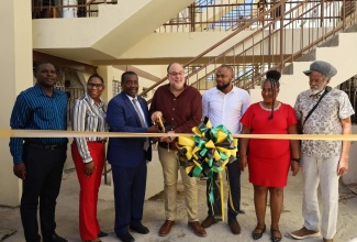 Minister without Portfolio in the Ministry of Economic Growth and Infrastructure Development with Responsibility for Land Titling and Settlements, Hon. Robert Montague (third left), and Opposition Leader and Member of Parliament for St. Andrew Southern, Mark Golding (centre), cut the ribbon to mark the completion of the $58-million Torrington Park Housing Rehabilitation Project on December 9. They are joined by (from left) Caretaker for St. Andrew Southern, Carlton Allen; Ministry officials – Senior Director, Christina Gardner, and Director of Projects, Phillip Stephenson; Councillor for the Admiral Town Division, Louise Newland; and Contractor, Orrett Wellington.

