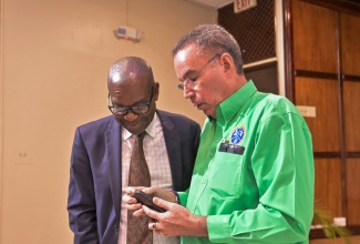 Minister of Energy, Transport and Telecommunications, Hon. Daryl Vaz (right), and Director General of the Office of Utilities Regulation (OUR), Ansord Hewitt, share a moment of interest during a press conference at the Ministry’s offices in the Petroleum Corporation of Jamaica (PCJ) Building in New Kingston on December 16.

