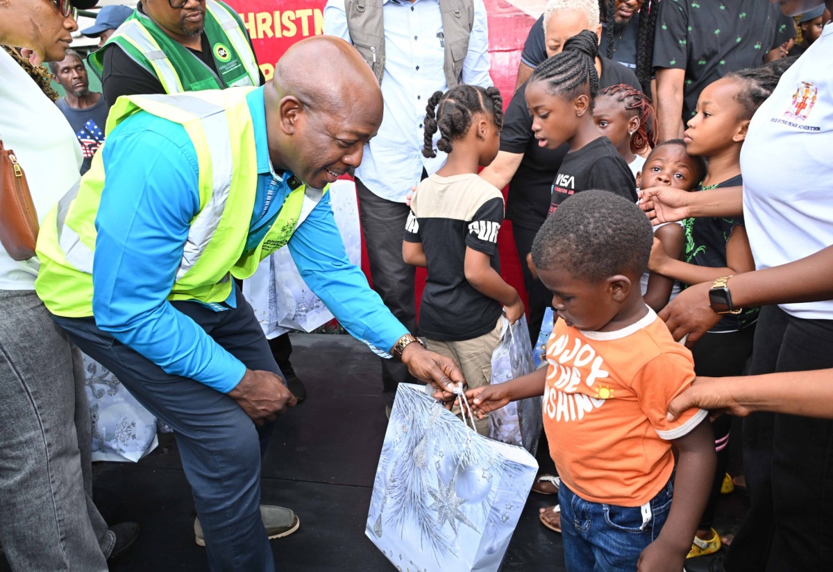 Minister of Labour and Social Security, Hon. Pearnel Charles Jr., distributes gifts during the Prime Minister’s Christmas Treat at the Petersfield High School shelter in Westmoreland on Saturday (December 13).