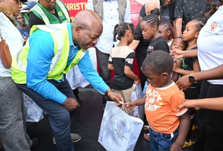 Minister of Labour and Social Security, Hon. Pearnel Charles Jr., distributes gifts during the Prime Minister’s Christmas Treat at the Petersfield High School shelter in Westmoreland on Saturday (December 13).