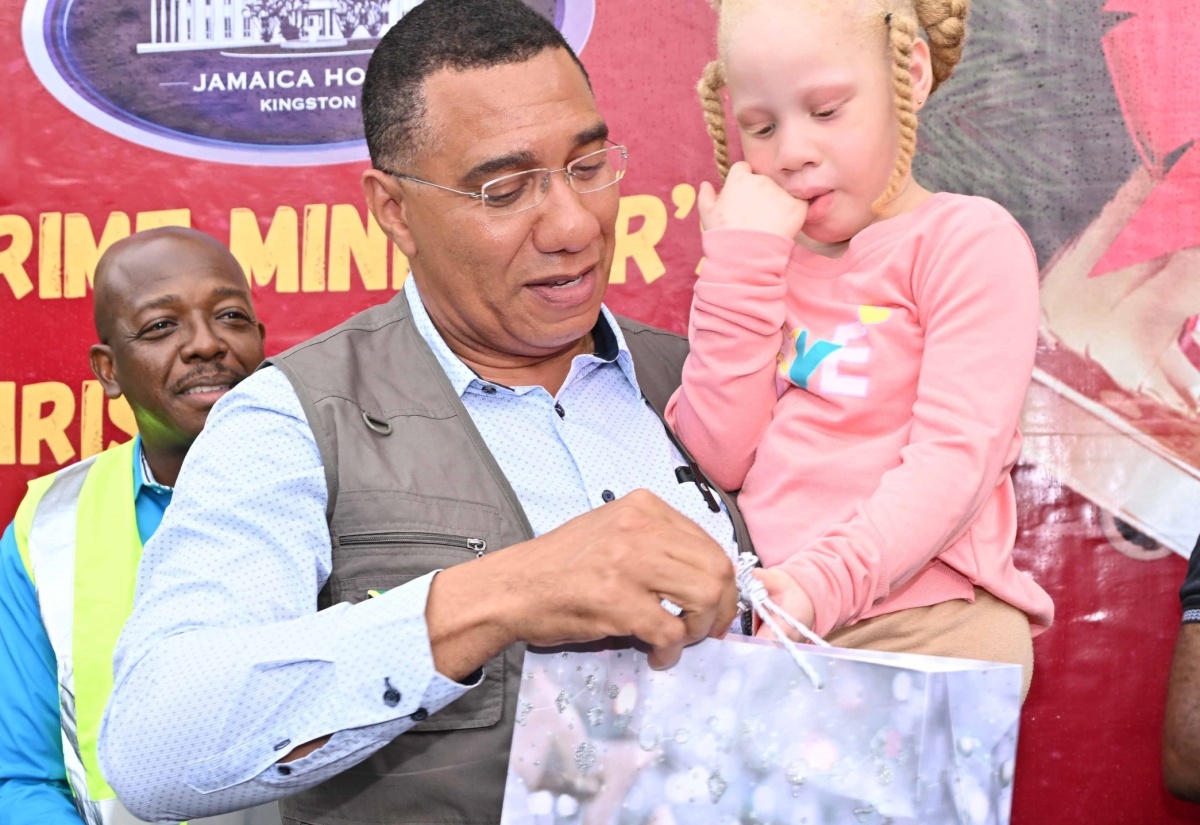 Prime Minister, Dr. the Most Hon. Andrew Holness gives a gift to a child, during a Christmas treat held at the Petersfield High School in Westmoreland on December 13. Also participating is Minister of Labour and Social Security, Hon. Pearnel Charles Jr (background, left).