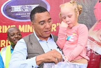 Prime Minister, Dr. the Most Hon. Andrew Holness gives a gift to a child, during a Christmas treat held at the Petersfield High School in Westmoreland on December 13. Also participating is Minister of Labour and Social Security, Hon. Pearnel Charles Jr (background, left).