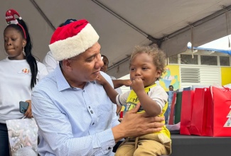 Prime Minister, Dr. the Most Hon. Andrew Holness interacts with a young child at a Christmas kiddies treat at the Middle Quarters Primary and Infant School in St. Elizabeth, on December 13.