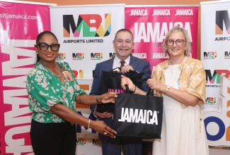 Jamaica Tourist Board (JTB) Regional Manager, Odette Dyer (left), presents a gift of appreciation to High Commissioner of Canada to Jamaica, His Excellency Mark Berman (centre), following the arrival of the inaugural WestJet flight from Quebec into the Sangster International Airport, Montego Bay, St. James on December 6. Also in photo is Her Excellency Allison Berman, wife of the High Commissioner.

