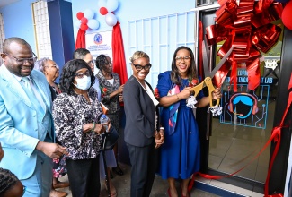 Permanent Secretary in the Ministry of Education, Skills, Youth and Information, Dr. Kasan Troupe (right), cuts the ribbon to officially open the Electronic Document Preparation and Management (EDPM) and Customer Engagement Laboratory at Stony Hill Technical High School in St. Andrew on Friday (January 9). Joining her are State Minister in the Ministry of National Security and Peace and Member of Parliament for St. Andrew West Rural, Hon. Juliet Cuthbert Flynn (second right), along with other stakeholders.