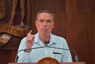 Minister of Energy, Telecommunications and Transport, Hon. Daryl Vaz, hails former Permanent Secretary, Carol Palmer, during a recent post-Cabinet press briefing held at Jamaica House.

