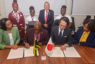 Minister of State in the Ministry of Education, Skills, Youth and Information, Hon. Rhoda Moy Crawford (seated left), observes as Principal of Muschette High School in Trelawny, Leighton Johnson (seated, second left), and Japan’s Ambassador to Jamaica, His Excellency Kohei Maruyama, sign an agreement for the provision of two school buses for the institution on Tuesday (January 27) at the Education Ministry’s Student Assessment Unit Conference Room, Caenwood Centre, Kingston. Also participating are Executive Director of the National Education Trust, Latoya Harris-Ghartey; Board Chairman of Muschette High School, Paul Muschette, and students of the institution.

