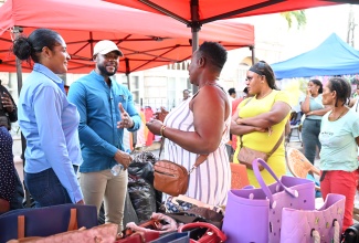 Mayor of Montego Bay and Chairman of the St. James Municipal Corporation, Councillor Richard Vernon, along with Chief Executive Officer, Naudia Crosskill (left), engages vendor, Minorah Robinson (centre), and others during a visit with vendors across downtown Montego Bay on Friday (January 9).

