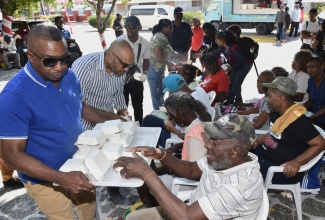 Mayor of Kingston, Councillor Andrew Swaby (standing left), along with Chief Executive Officer of the Kingston and St. Andrew Municipal Corporation (KSAMC) and Town Clerk, Robert Hill (second left), serves meals to homeless, elderly, and other vulnerable persons during the Mayor’s annual New Year’s Day Feeding on Thursday (January 1) at St. William Grant Park in downtown Kingston.

