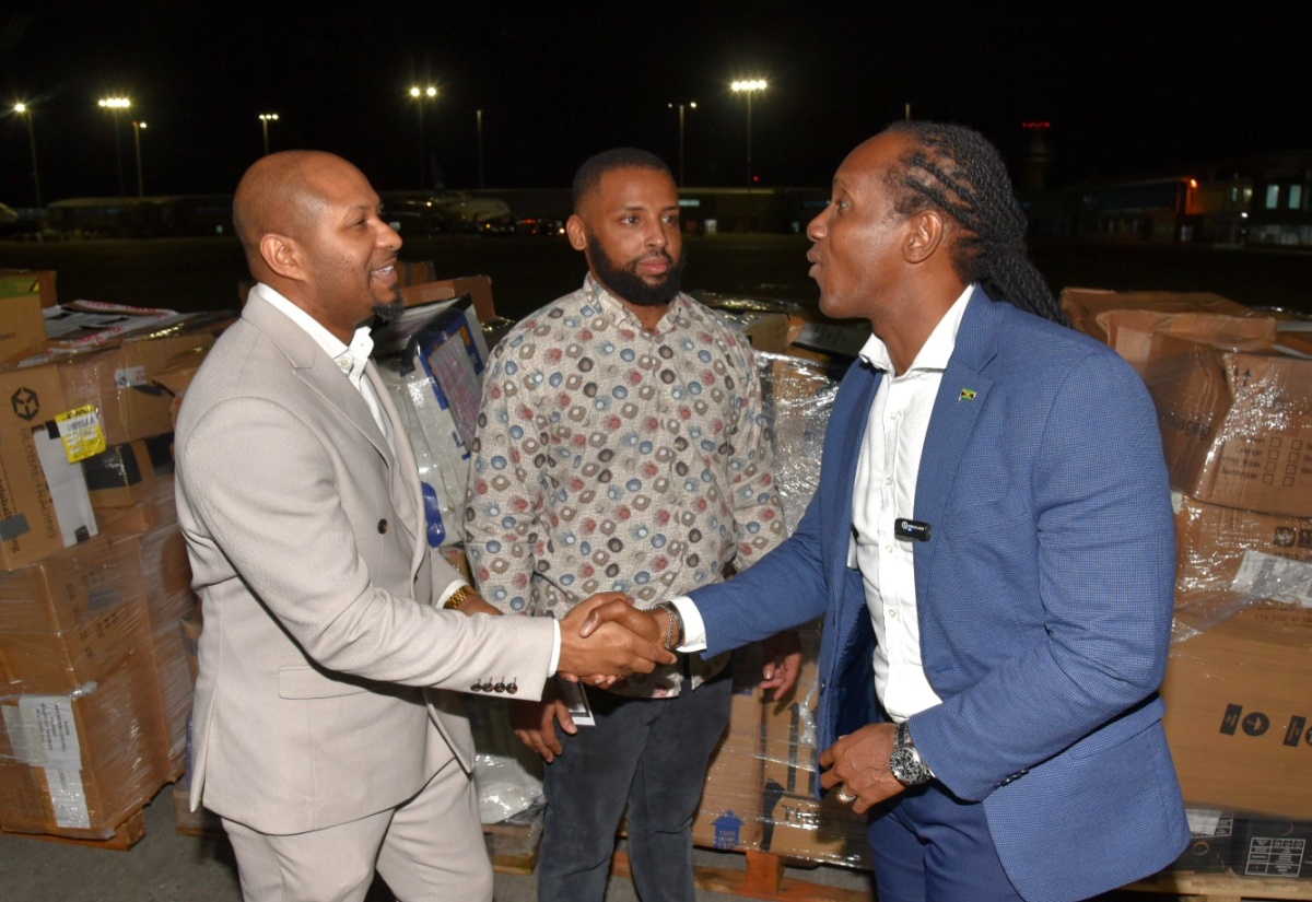 State Minister in the Ministry of Foreign Affairs and Foreign Trade, Hon. Alando Terrelonge (right), shakes hands with Global Jamaica Diaspora Council United Kingdom (UK) South representative and Chief Executive Officer of Jamaicans Inspired, Nathaniel Peat (left), at the handover of humanitarian supplies donated by the UK Diaspora on Friday (January 16) at the Norman Manley International Airport in Kingston. Looking on is CEO of Fantasy Wings, Jackson Smith.


