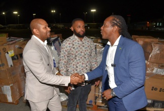 State Minister in the Ministry of Foreign Affairs and Foreign Trade, Hon. Alando Terrelonge (right), shakes hands with Global Jamaica Diaspora Council United Kingdom (UK) South representative and Chief Executive Officer of Jamaicans Inspired, Nathaniel Peat (left), at the handover of humanitarian supplies donated by the UK Diaspora on Friday (January 16) at the Norman Manley International Airport in Kingston. Looking on is CEO of Fantasy Wings, Jackson Smith.

