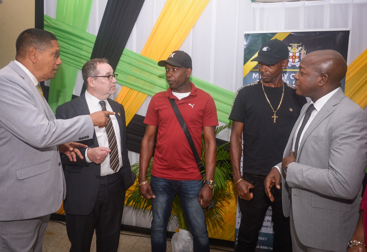 State Minister in the Ministry of Labour and Social Security, Hon. Donovan Williams (left), speaks with farm workers André Ellis (centre) and Arnold Campbell (second right), during a send-off for participants in the Canadian Seasonal Agricultural Workers Programme (SAWP)  this month at the Ministry’s Overseas Employment Centre on East Street in downtown Kingston.  High Commissioner of Canada to Jamaica, His Excellency Mark Berman (second left), and Minister of Labour and Social Security, Hon. Pearnel Charles Jr. (right), share in the discussion.

