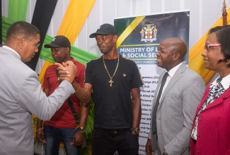 State Minister in the Ministry of Labour and Social Security, Hon. Donovan Williams (left), greets farmworker, Arnold Campbell (centre), at a send- off for seasonal agricultural workers to Canada, held at the Ministry’s Overseas Employment Centre on East Street in downtown Kingston, on January 6. Others from (second left) are farmworker André Ellis; Minister of Labour and Social Security, Hon. Pearnel Charles Jr. and Permanent Secretary in the Ministry, Dione Jennings.

