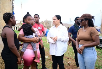 Custos of Clarendon, Hon. Edith Chin (second left), speaks with Ashella Baker (second left) from Middle Quarters in St. Elizabeth, while in the community recently to hand over a container house to the mother of six. Sharing in the discussion is representative of non-profit organisation, Community Organized Relief Effort (CORE), Shelly-Ann James (right), while three of Miss Baker