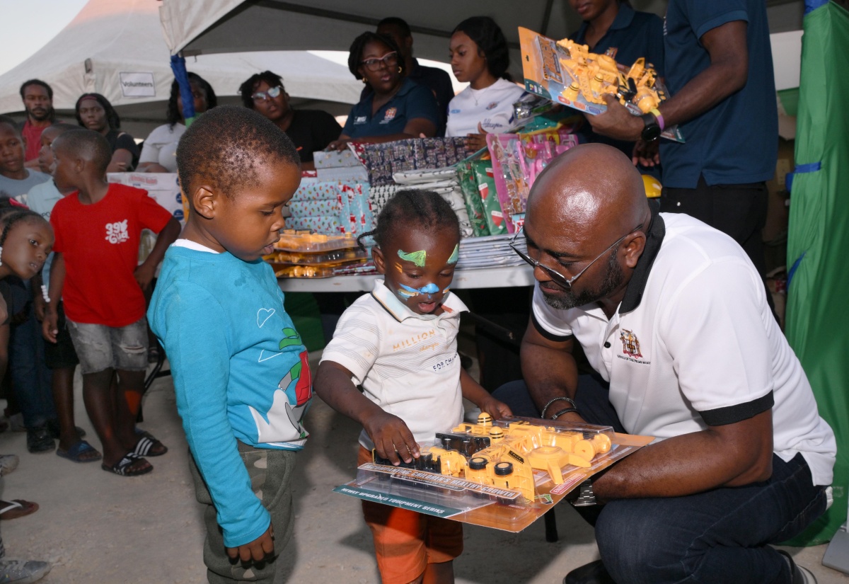 Minister Without Portfolio in the Office of the Prime Minister responsible for Science, Technology and Special Projects, Dr. the Hon. Andrew Wheatley, hands out gifts to children in Black River, during the Kiddies Treat segment of the Urban Development Corporation