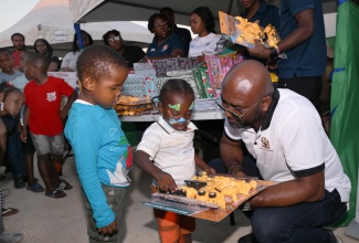 Minister Without Portfolio in the Office of the Prime Minister responsible for Science, Technology and Special Projects, Dr. the Hon. Andrew Wheatley, hands out gifts to children in Black River, during the Kiddies Treat segment of the Urban Development Corporation