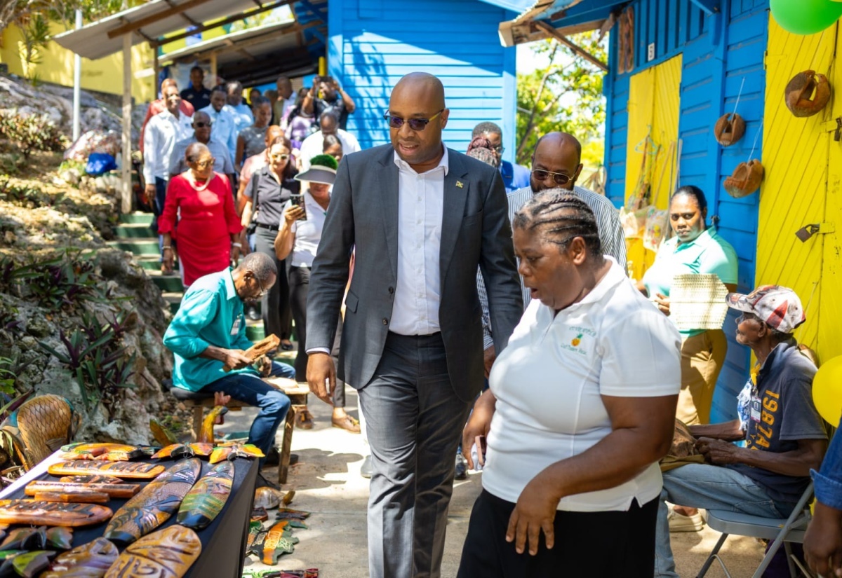 Minister of State in the Ministry of Industry, Investment and Commerce, Hon. Delano Seiveright (centre), is accompanied by President of the Pineapple Craft Traders Association, Claire Bruce (right), on a tour of the Pineapple Craft Market in Ocho Rios, St. Ann.

